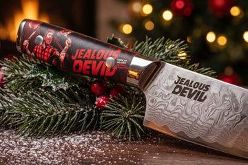Jealous Devil kitchen knife with a patterned blade displayed with Christmas greenery