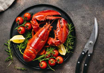 Whole cooked lobster served with lemon, cherry tomatoes and fresh herbs