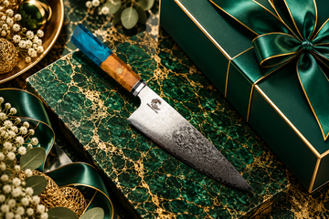 Premium Damascus chef’s knife on emerald green marble with gold accents and luxury gift packaging.