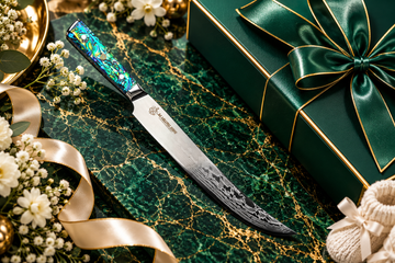 Damascus kitchen knife on emerald green marble with gold accents and luxury gift packaging for employees welcoming a new baby.