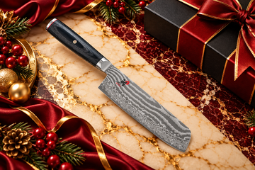 Premium Damascus kitchen cleaver with a black wood-grain handle displayed on burgundy and cream marble with gold accents, festive red ribbons, and elegant Christmas gift decorations for corporate gifting.