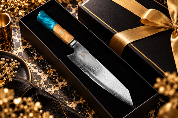 Premium chef’s knife in a black gift box with gold ribbon on a black marble surface.