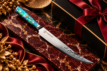 Premium kitchen knife with an iridescent handle on burgundy marble, paired with black and gold gift packaging and red satin ribbon.